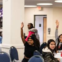 Girls of Color Summit previous event attendees raising hands to answer a question